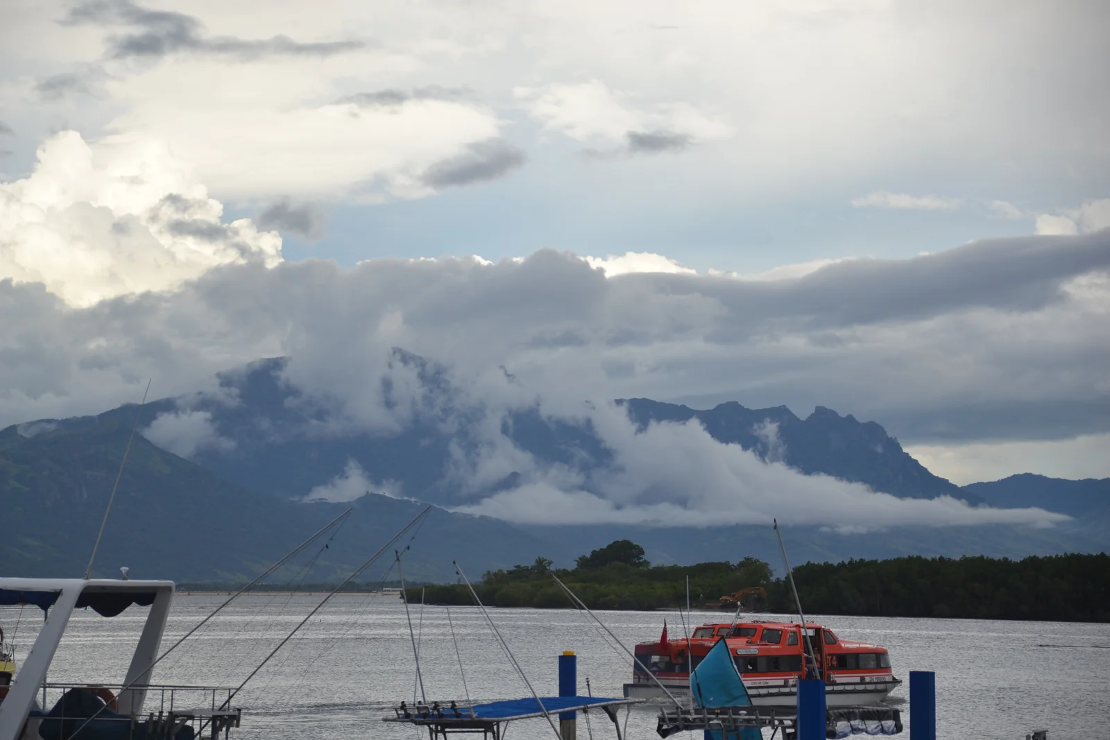 Boats at Denarau Marina with low cloud drifting across the mountains beyond the bay